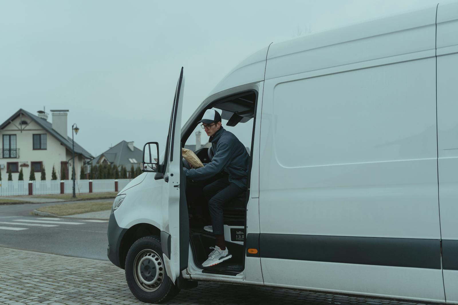 Courier delivering a package from a van in suburban neighborhood, showcasing logistics and last-mile delivery services.