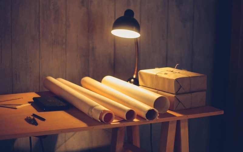 a table with a lamp and some rolls of paper on it