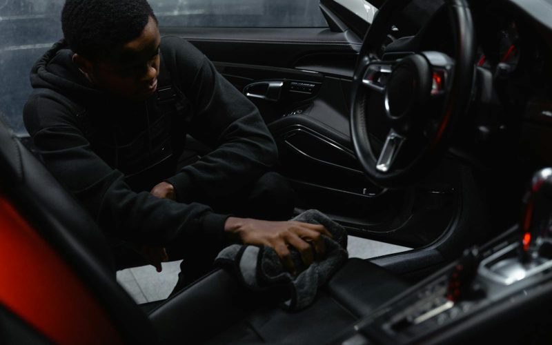 A man wipes the interior of a car for a thorough cleaning, focusing on detailing and maintenance.