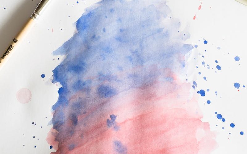 Vibrant watercolor painting with blue and red gradient, brush, and palette.
