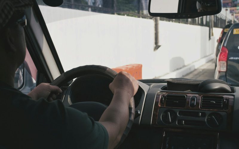 person driving vehicle on road near vehicle at daytime